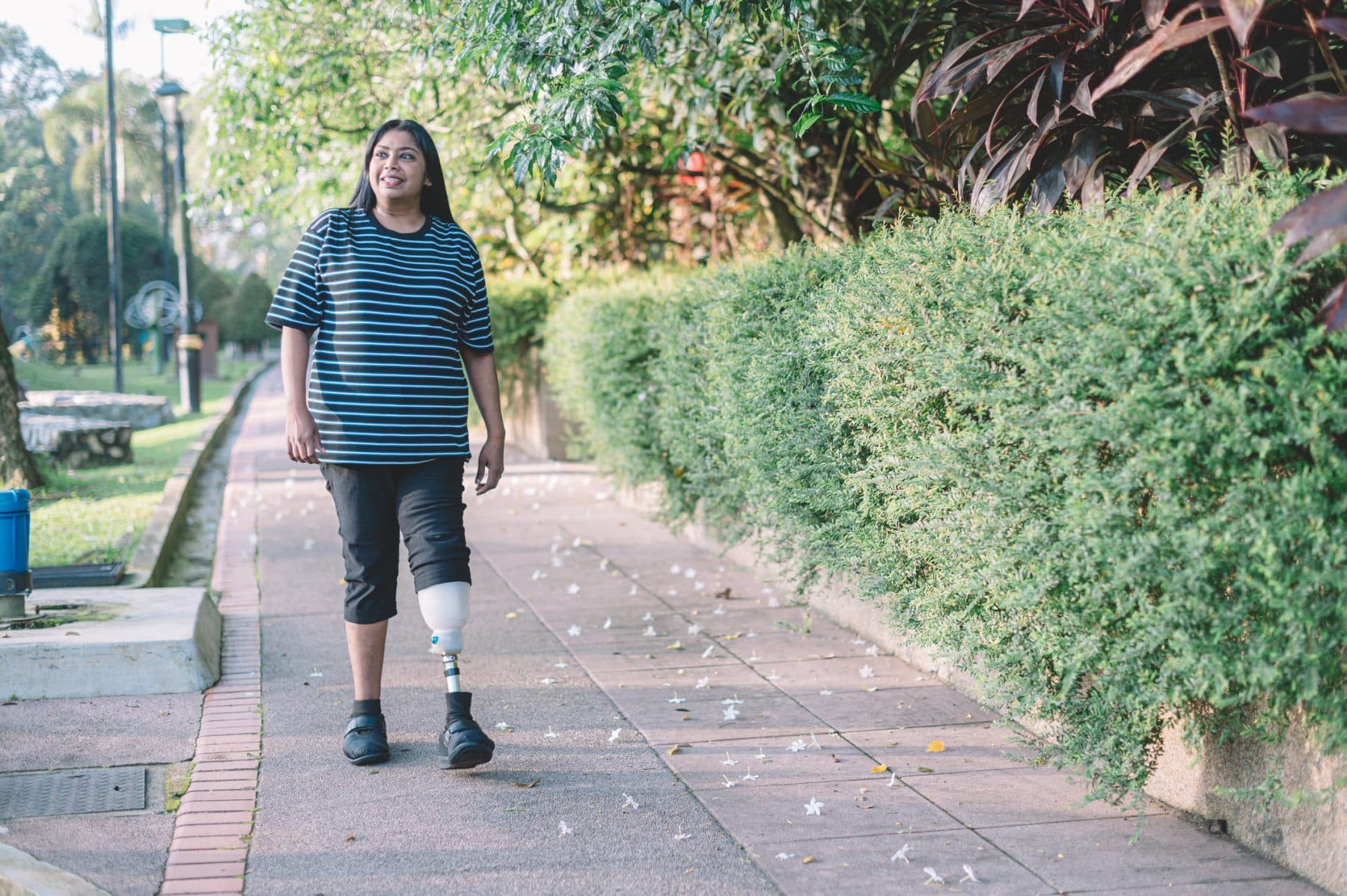 A woman with a prosthetic leg walking down the sidewalk in Orange County.