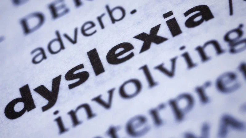 Close-up of the word "dyslexia" in bold print from a dictionary, with surrounding text slightly blurred.