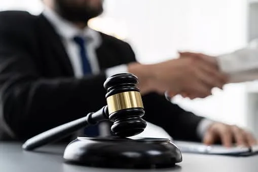 A Supplemental Security Income lawyer in Whittier shakes hands with his client. A gavel and sound block sit in the foreground.