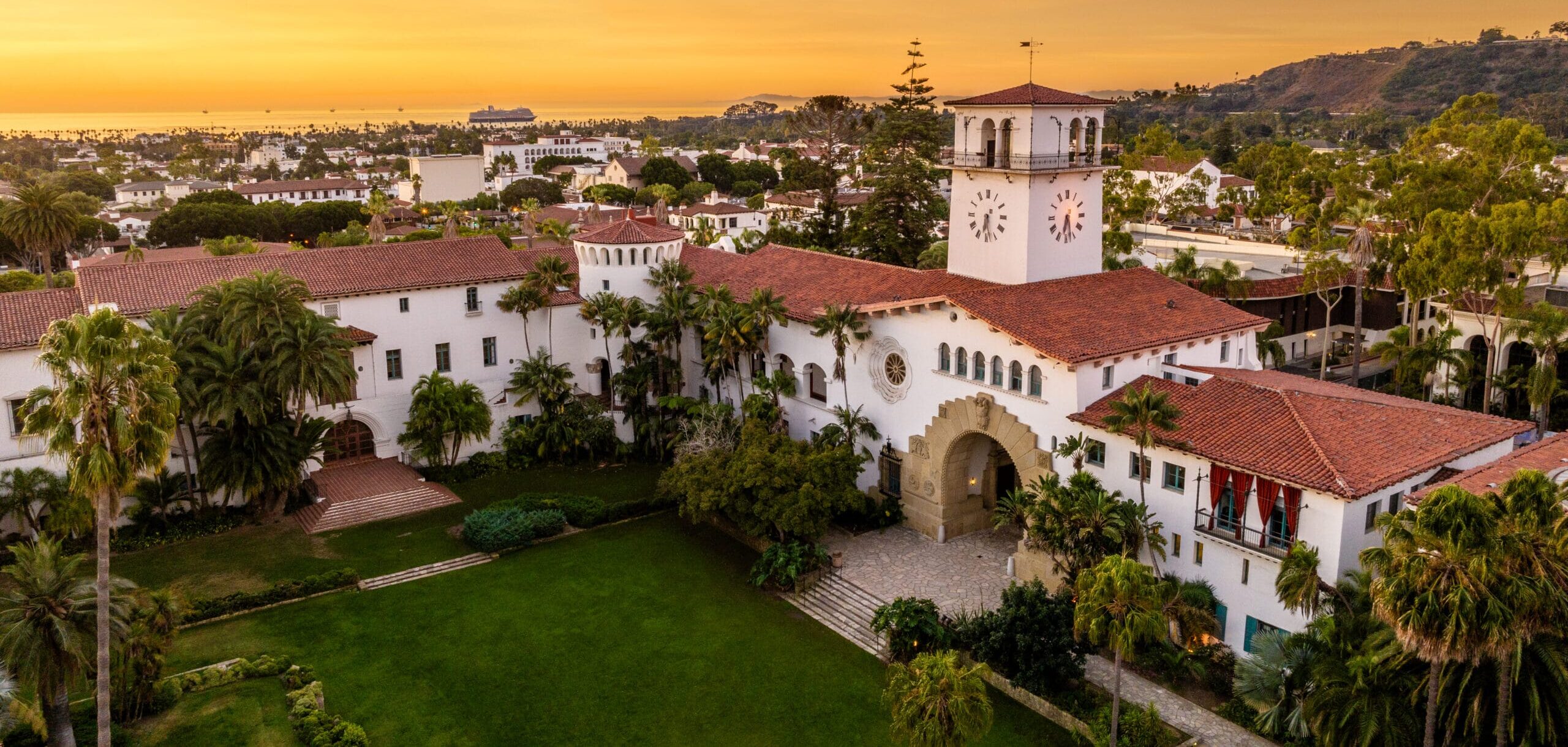 Aerial view of the Santa Barbara County Courthouse and surrounding cityscape at sunset.