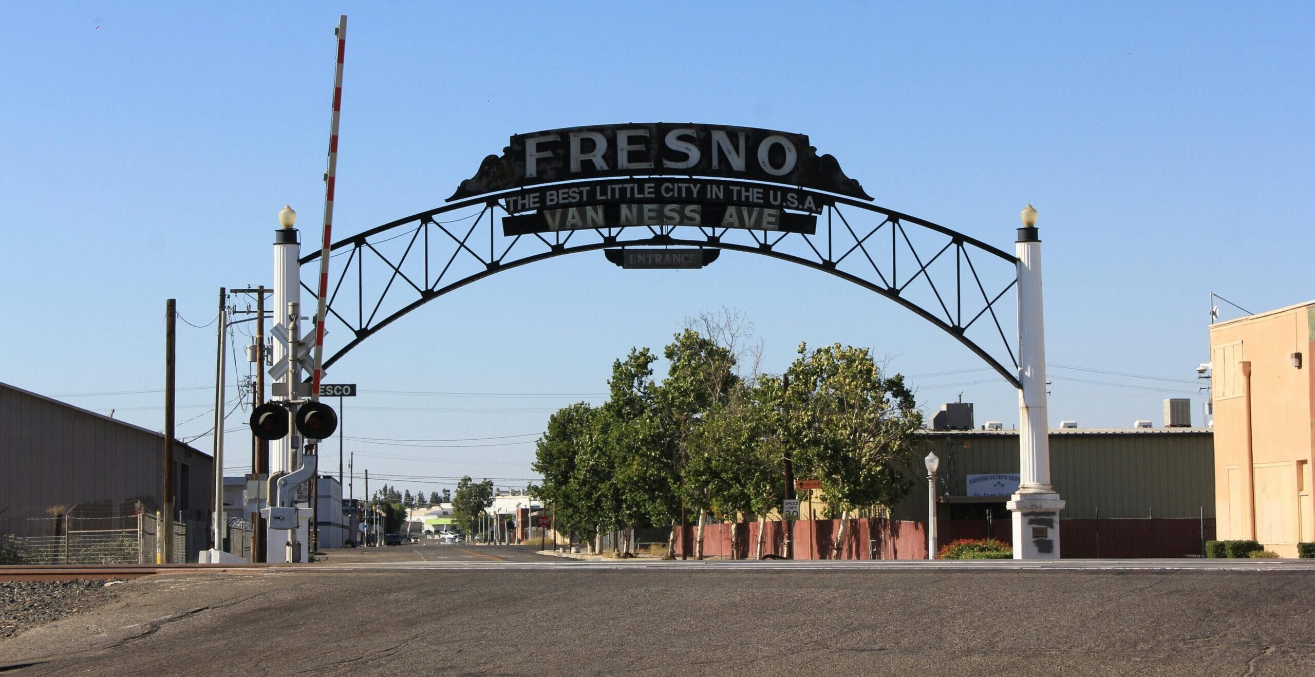 Historic Fresno arch reading “Fresno – The Best Little City in the U.S.A.” spanning Van Ness Avenue under a clear blue sky.